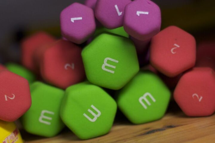 A pile of hexagonal dumbbells in green, red, and purple, labeled with white numbers and the letter 