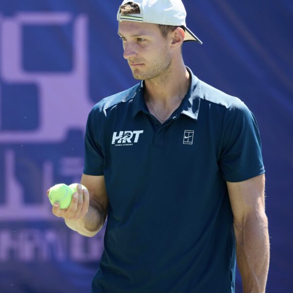 Male tennis pro, Hugo Colpart, in white hat and blue shirt
