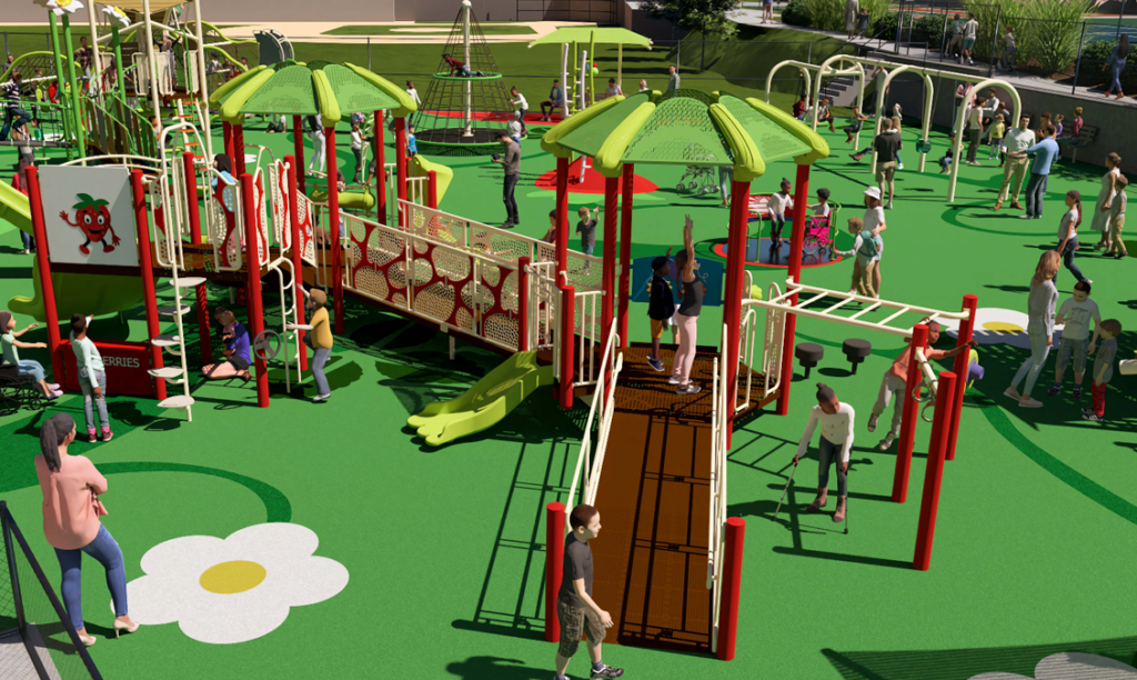 Children and adults are playing on a colorful, accessible playground with slides, bridges, and various climbing structures on a green, flower-patterned surface.