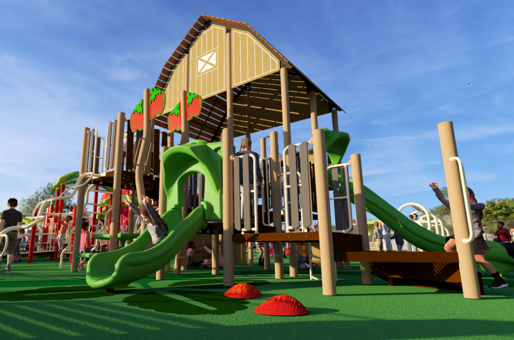 Children play on a large playground structure with slides, ramps, and a barn-like roof under a clear blue sky.